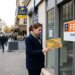Personne tenant une carte bancaire gold face à une agence bancaire fermée en France