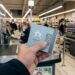 Carte cadeau prepayee bitcoin tenue en main pres d'une caisse de supermarche