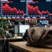 Sac en cuir en premier plan devant un graphique boursier en baisse