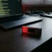 Portefeuille matériel de cryptomonnaie posé près d'un écran affichant du code informatique
