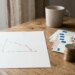 Pièces et billets en euros près d'un graphique en baisse illustrant l'inflation
